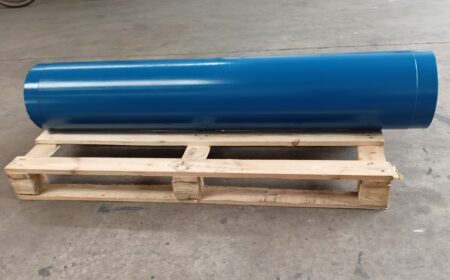 A blue-painted stator lies crosswise on a wooden pallet. It protrudes slightly above the pallet so that its size can be recognised.